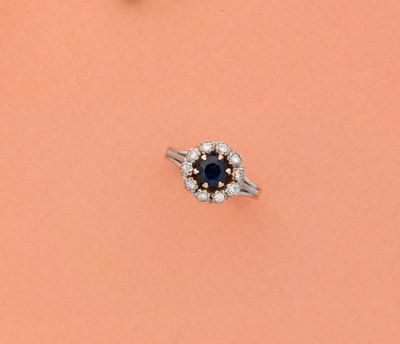 un gros plan d'une bague sertie d'un diamant et d'un saphir, posée sur un fond rose