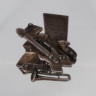 Broche en métal argenté vers 1980 figurant un trophée d'inst…