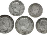 six types différents de pièces d'argent sont représentés sur une surface blanche