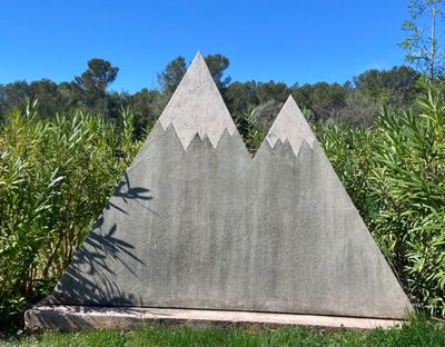 a concrete sculpture of a mountain with trees in the background