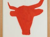 une photo représentant une tête de taureau rouge sur un mur blanc