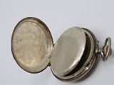 a close up of a silver pocket watch on a white surface