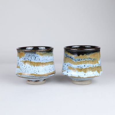 deux petites tasses sont posées côte à côte sur une surface blanche