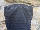 un sac noir posé sur un poteau en bois près d'un mur de pierre