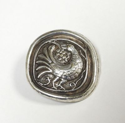 an antique silver button with a lion on it on a white surface