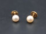 a pair of pearl earrings on a black surface