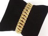 un gros plan d'un bracelet à maillons dorés posé sur un coussin noir