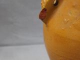 a yellow vase with a green leaf on the top of it