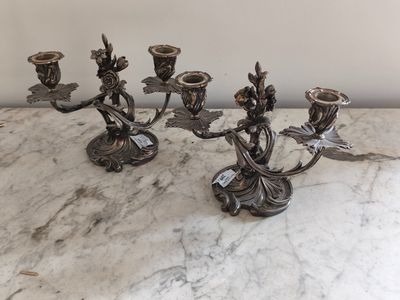 Quatre bougies sont posées sur une table en marbre, avec un mur blanc en arrière-plan.