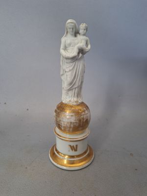 une statue représentant une femme tenant un enfant dans ses bras, posée sur un socle