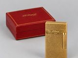 a gold plated lighter with a red box on a white surface