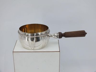 a silver bowl with a wooden handle on a white pedestal