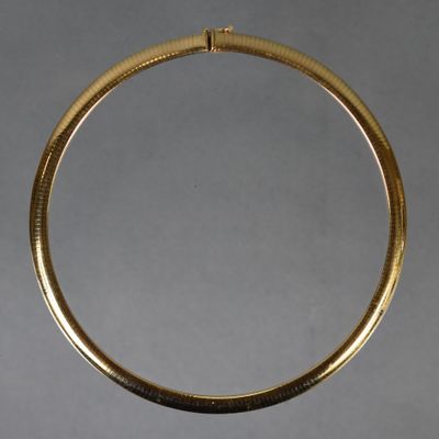 gros plan d'un collier en or sur une surface blanche