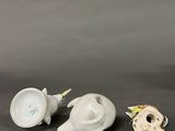 two small white and yellow vases sitting next to each other on a table