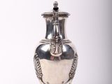 an image of a silver vase sitting on a stand on a white surface