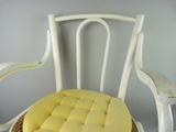 a wicker chair with a yellow cushion on it