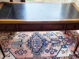 un bureau au plateau noir posé sur un tapis dans une pièce