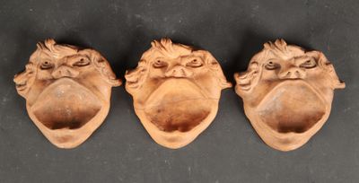 three carved heads of monkeys on a black surface