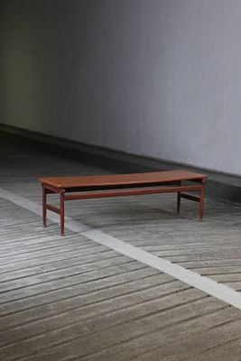 un banc en bois posé sur un parquet, dans une pièce vide