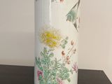 un vase blanc avec des fleurs posé sur une table