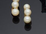 two pairs of pearls and a ring on a black surface