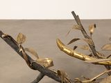 a gold sculpture of a branch with leaves on it
