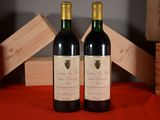 two bottles of red wine sitting next to each other on a table