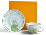 une tasse et une soucoupe posées à côté d'une boîte orange