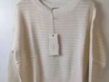 a white sweater hanging on a hanger on a wall