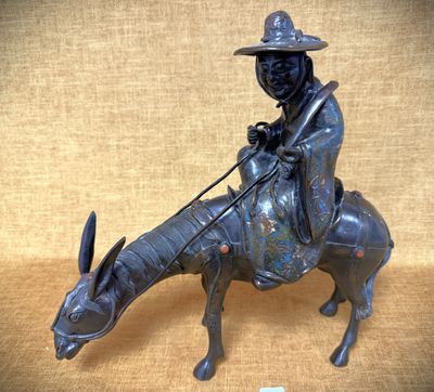 statue en bronze représentant un homme chevauchant une vache, coiffé d'un chapeau