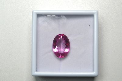 un saphir rose dans un écrin blanc posé sur une surface blanche