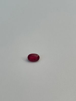 a single red stone sitting on top of a white surface
