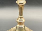 a gold candle holder on a table with a black background