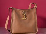 beige leather purse with gold metal hardware on a shiny surface