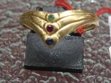 a gold ring with a red string and a blue and green stone