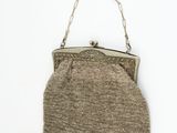 an old purse hanging on a chain on a white wall