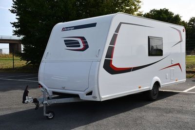 un petit camping-car blanc garé sur un parking