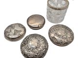 Plusieurs objets en argent sont posés sur une surface blanche.