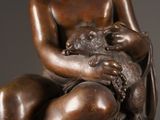 bronze statue of a woman holding a baby and holding a cat