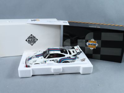 une petite voiture blanche dans une boîte blanche, à côté d'une boîte noire et blanche