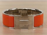 an orange bracelet with a silver clasp on a wooden surface