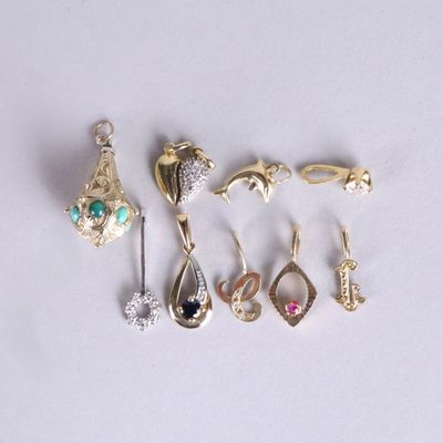 cinq paires de boucles d'oreilles et une broche posées sur un fond blanc