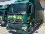 three green trucks parked in front of a building