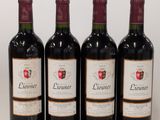 quatre bouteilles de vin sont alignées sur une surface blanche