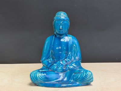 une statue de Bouddha en verre bleu posée sur une table en bois