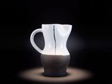 un vase blanc avec un socle noir sur fond noir