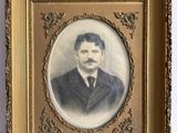 an old picture of a man in a suit and tie in a gold frame