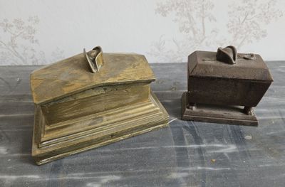 une paire de serre-livres anciens en laiton posés sur une table, avec un fond tapissé