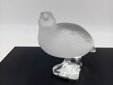 un oiseau en verre transparent posé sur une table noire