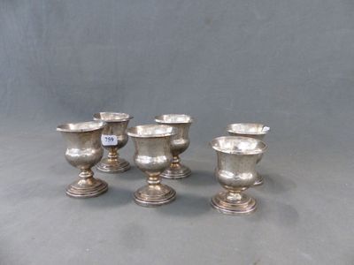 trois vases en argent posés l'un à côté de l'autre sur une table